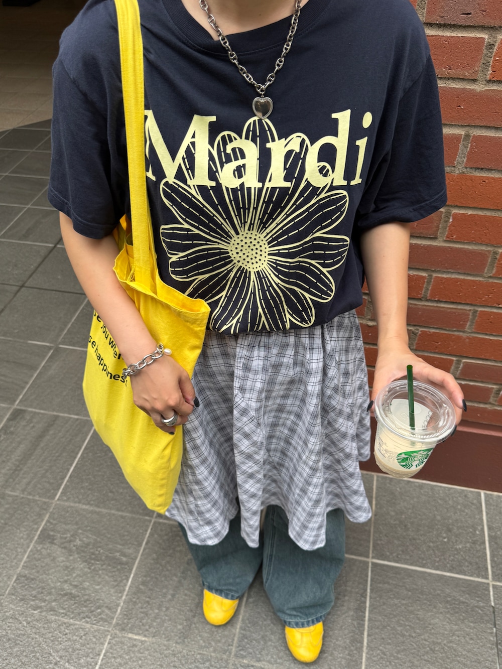 イエロー系のトートバッグ、ホワイト系のスカート、ブルー系のデニムパンツを着用したレディースの夏コーディネートの2枚目の写真