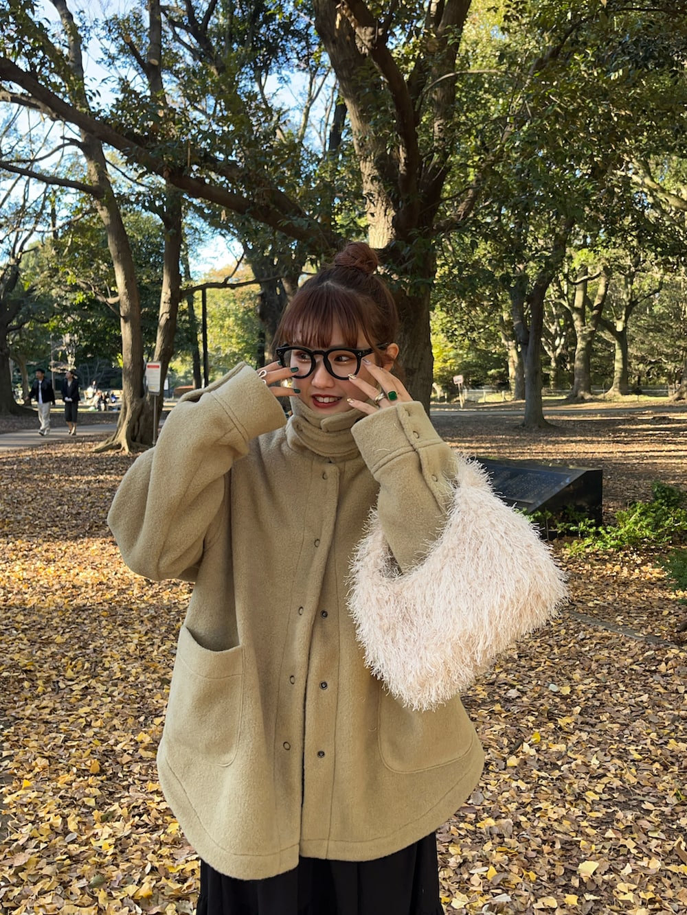 グリーン系のその他アウター、ブラック系のスカート、ホワイト系のハンドバッグを着用したレディースの冬コーディネートの2枚目の写真