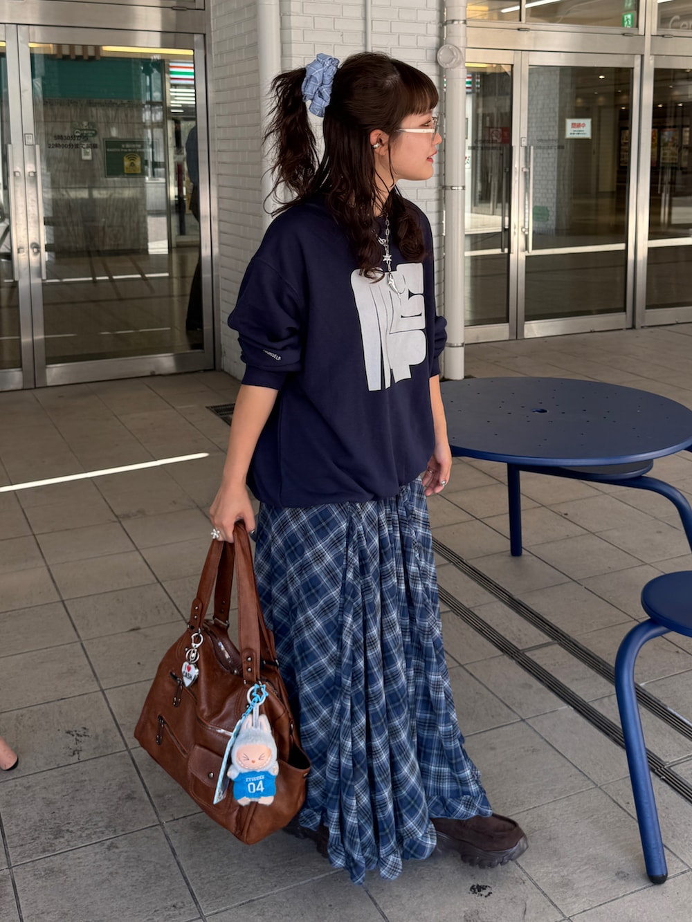 ブルー系のスウェット、ブラウン系のショルダーバッグ、ブルー系のスカートを着用したレディースの秋コーディネートの2枚目の写真
