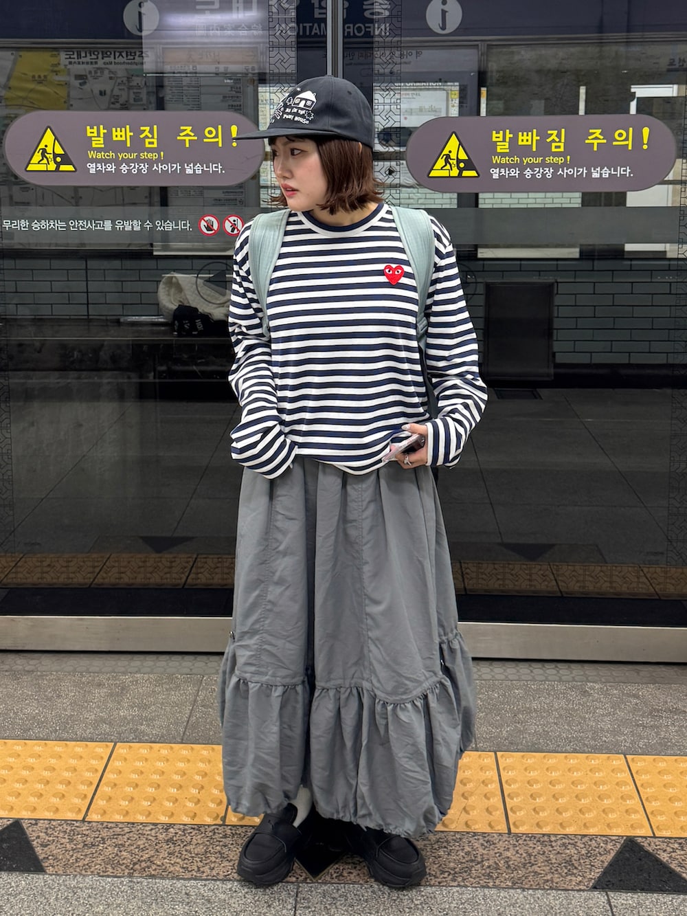 ブルー系のTシャツ/カットソー、グレー系のスカート、ブラック系のローファーを着用したレディースの春コーディネートの2枚目の写真