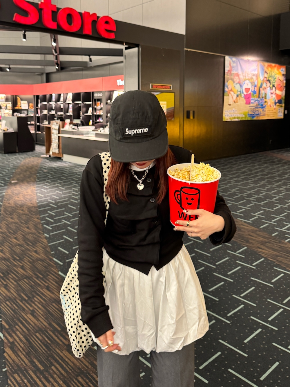 ホワイト系のトートバッグ、ブラック系のカーディガン/ボレロ、グレー系のスラックスを着用したレディースの冬コーディネートの2枚目の写真