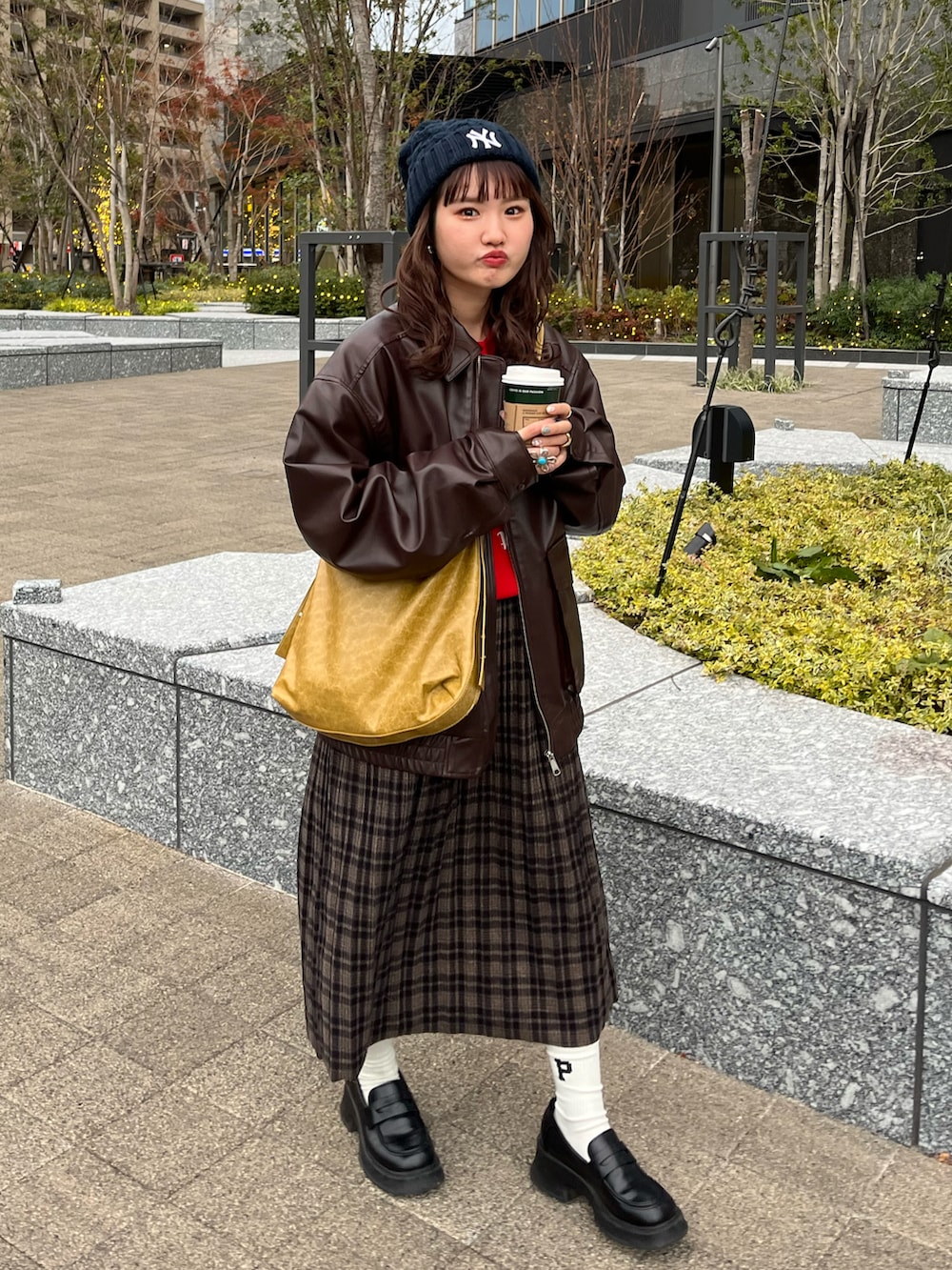 ブラウン系のライダースジャケット、イエロー系のショルダーバッグ、ブラウン系のスカートを着用したレディースの冬コーディネートの3枚目の写真