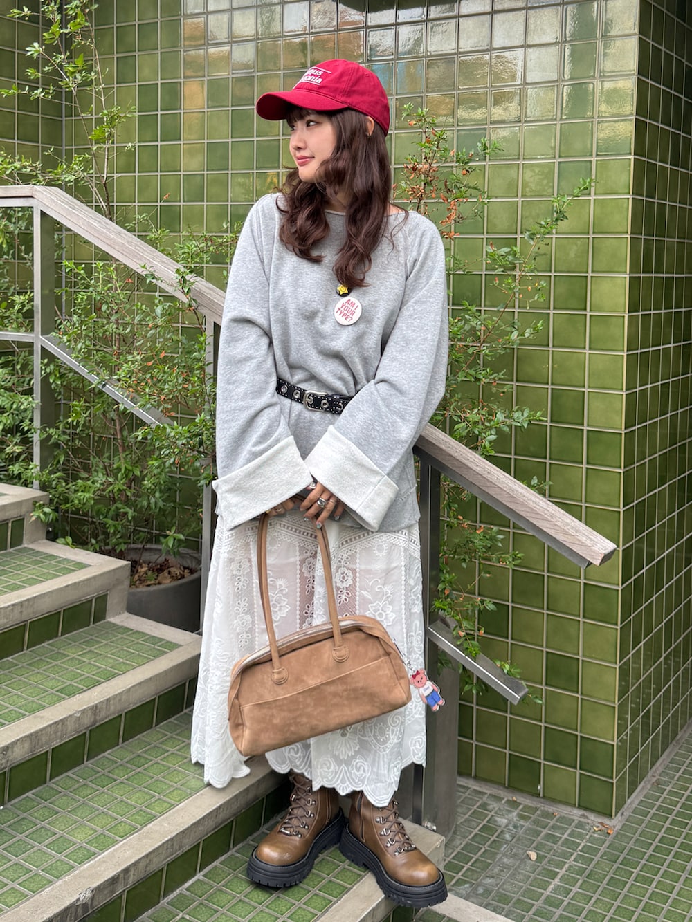 ベージュ系のボストンバッグ、グレー系のTシャツ/カットソー、ホワイト系のスカートを着用したレディースの秋コーディネートの2枚目の写真