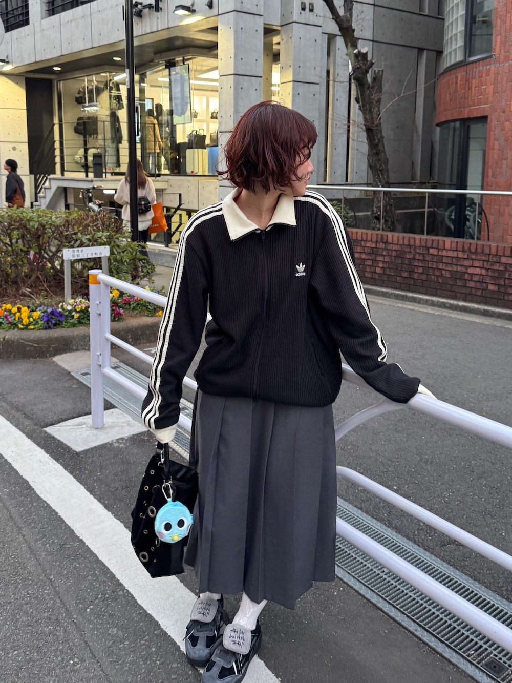 ブラック系のショルダーバッグ、ブラック系のジャージ、グレー系のスカートを着用したレディースの冬コーディネートの2枚目の写真