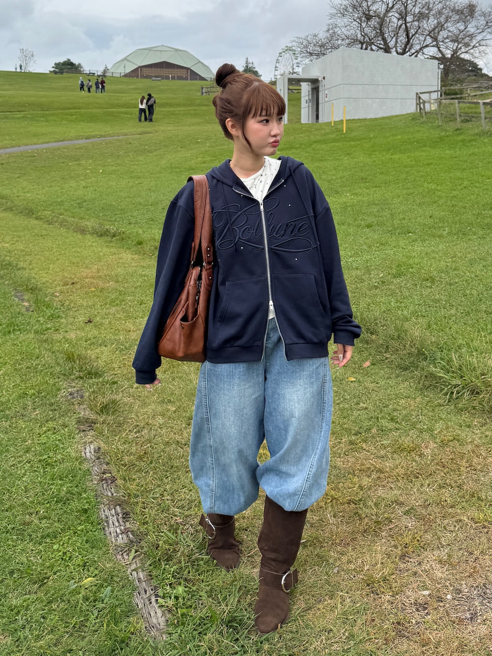 ブルー系のデニムパンツ、ブラック系のブーツ、ブルー系のパーカーを着用したレディースの秋コーディネートの2枚目の写真