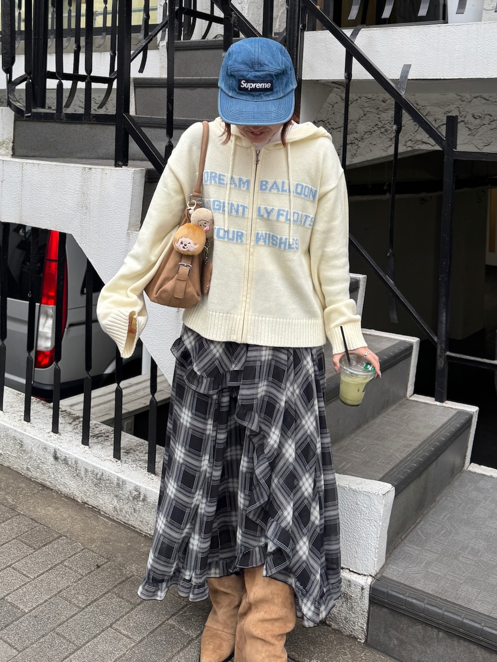 ブラック系のスカート、ホワイト系のニット/セーター、ベージュ系のバッグを着用したレディースの冬コーディネートの2枚目の写真