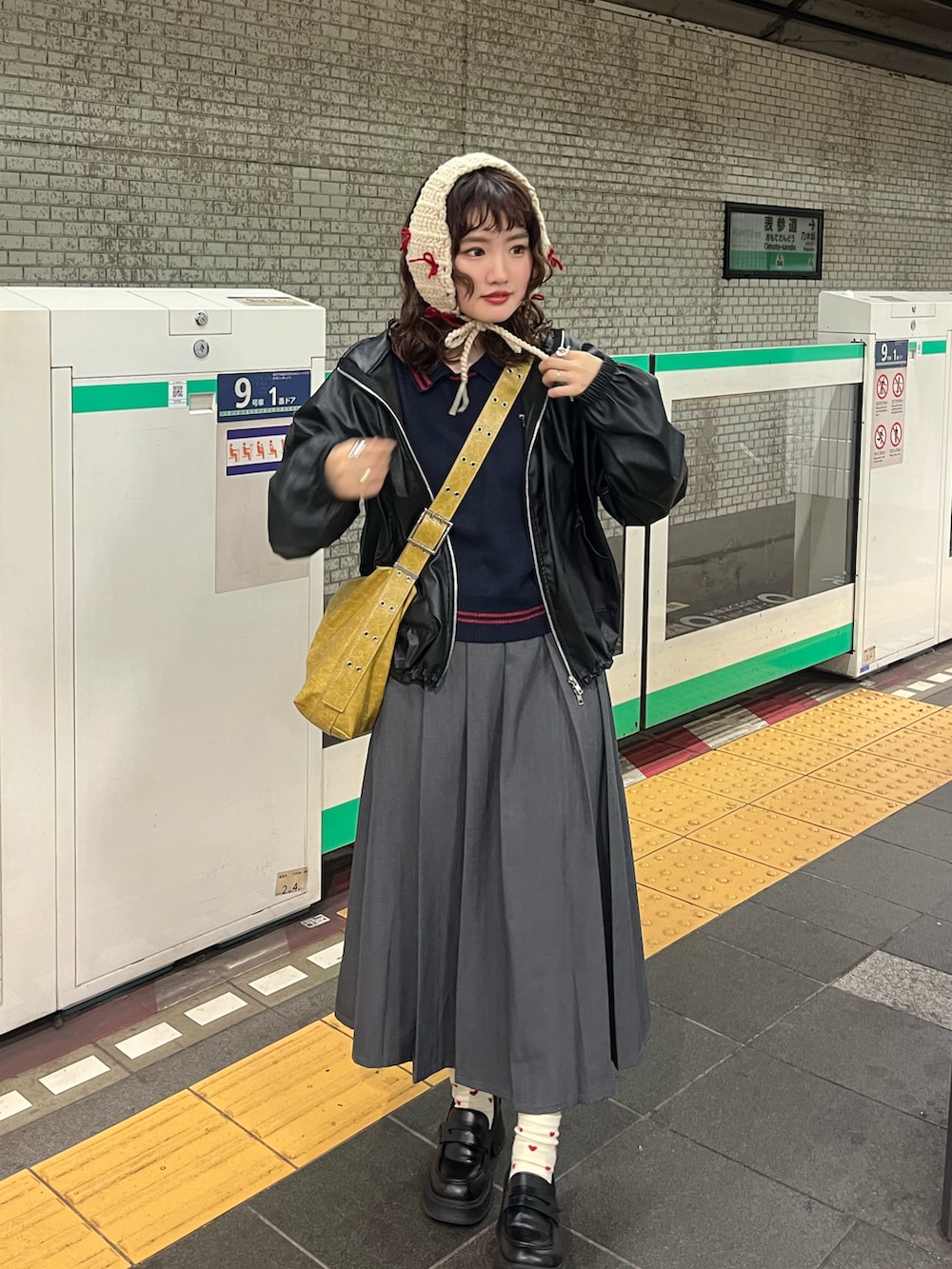 イエロー系のショルダーバッグ、ブラック系のニット/セーター、ブラック系のジャケット/アウターを着用したレディースの冬コーディネートの2枚目の写真