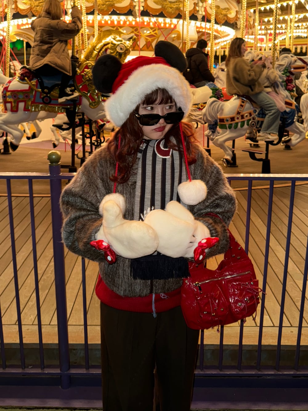 レッド系のハンドバッグ、ブラウン系のスラックス、ブラウン系のブルゾンを着用したレディースの冬コーディネートの2枚目の写真