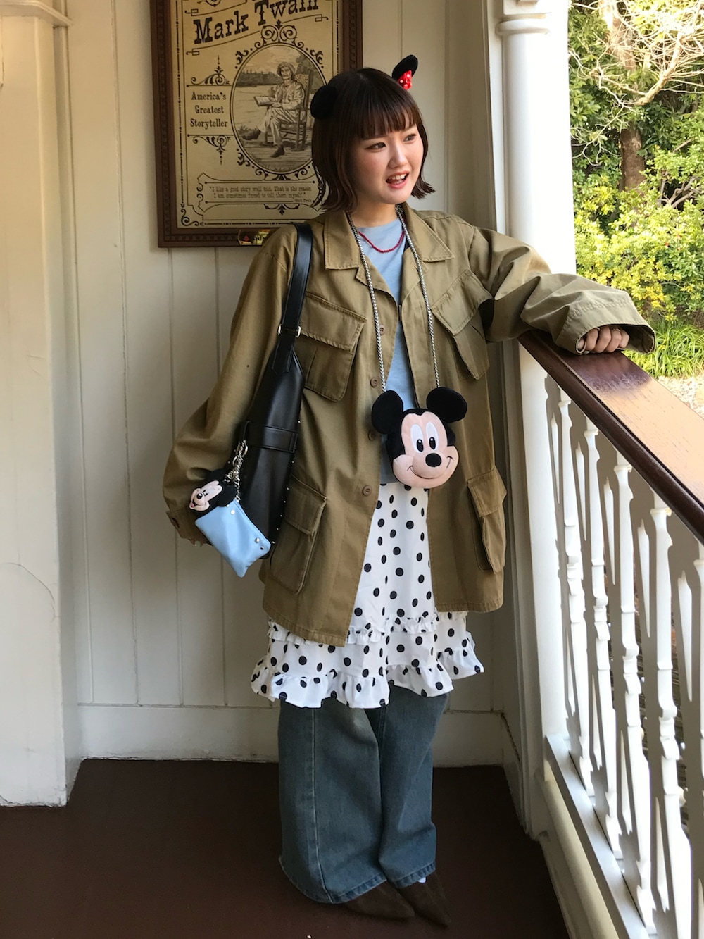 イエロー系のミリタリージャケット、ブルー系のデニムパンツ、ホワイト系のスカートを着用したレディースの春コーディネートの2枚目の写真