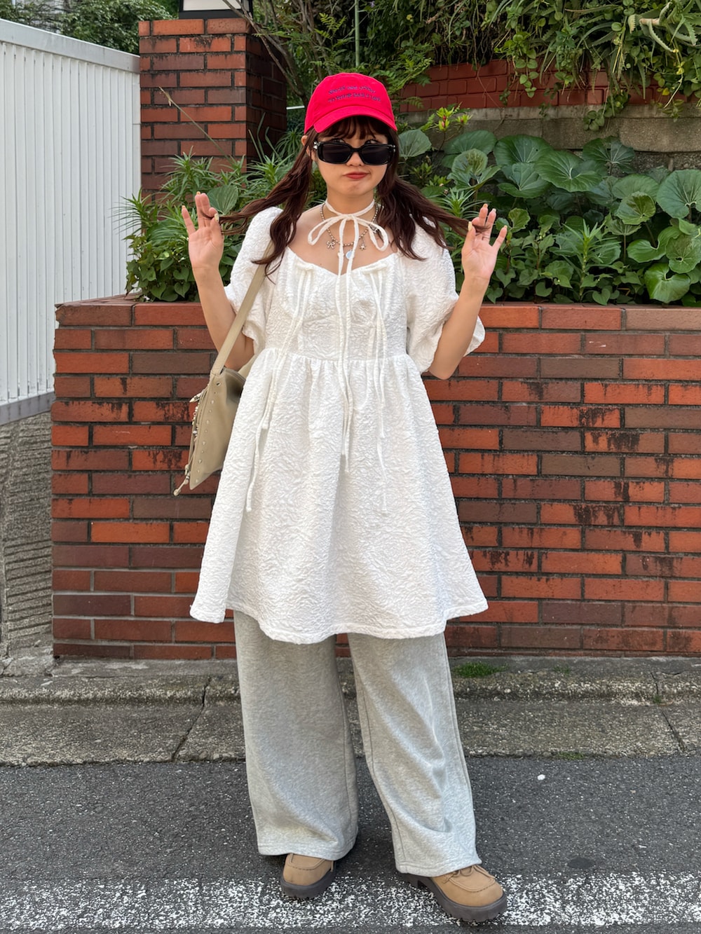 ホワイト系のワンピース、グレー系のスウェットパンツ、ベージュ系のハンドバッグを着用したレディースの春コーディネートの2枚目の写真