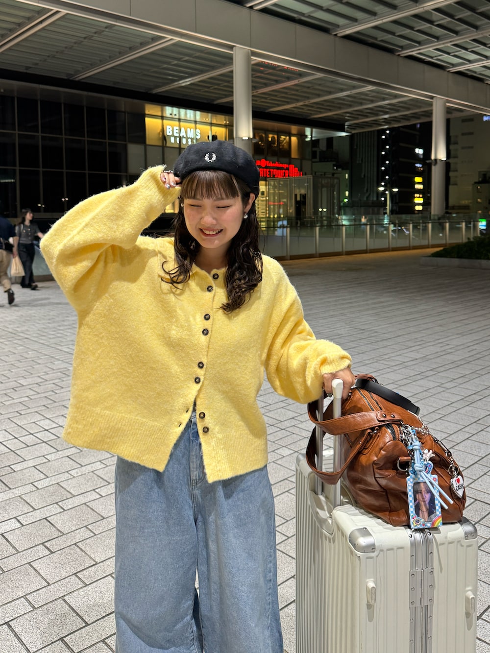 イエロー系のカーディガン/ボレロ、ブルー系のデニムパンツ、ブラウン系のブーツを着用したレディースの秋コーディネートの2枚目の写真