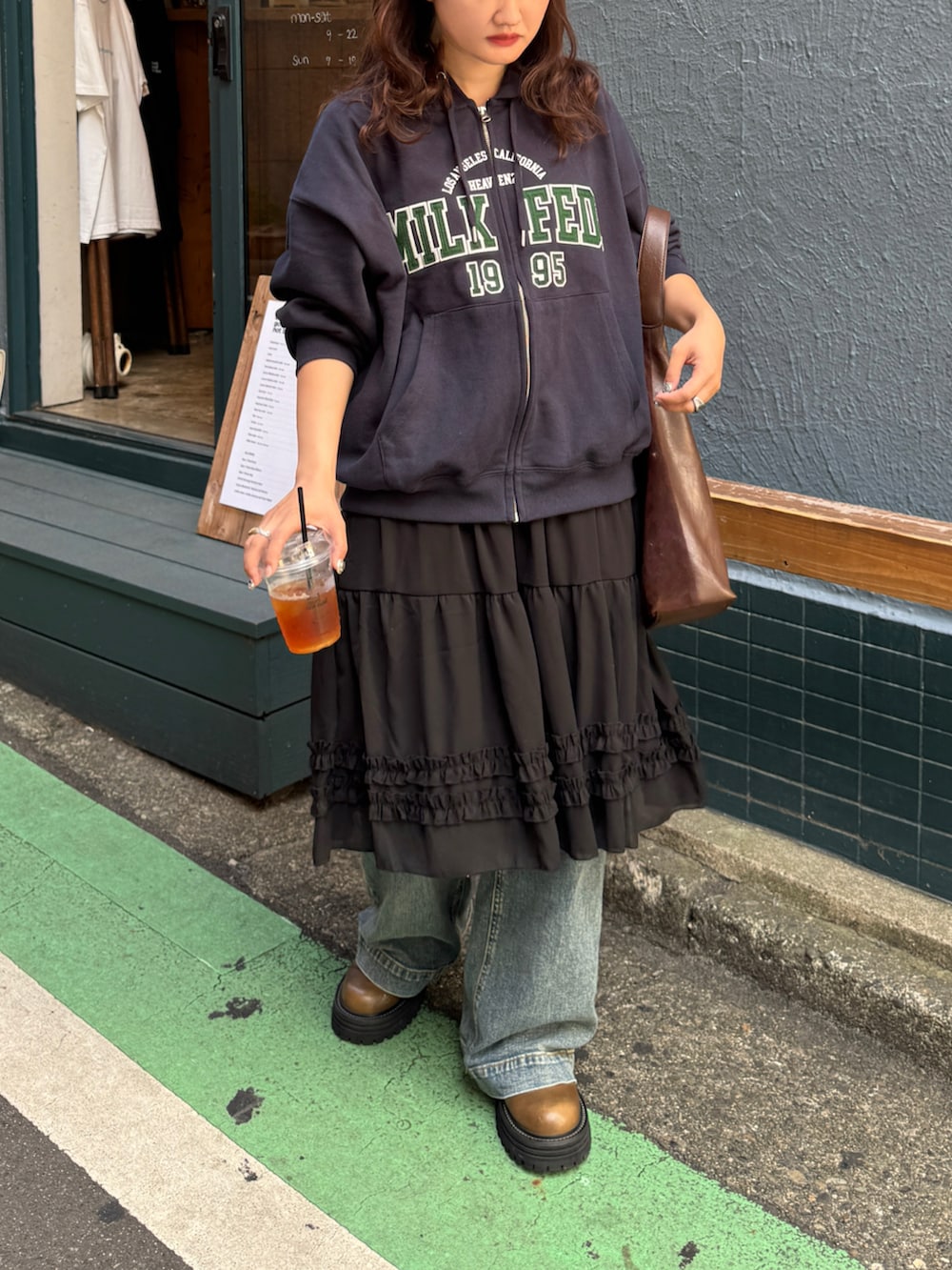 ブルー系のパーカー、ブルー系のデニムパンツ、ブラック系のスカートを着用したレディースの秋コーディネートの3枚目の写真