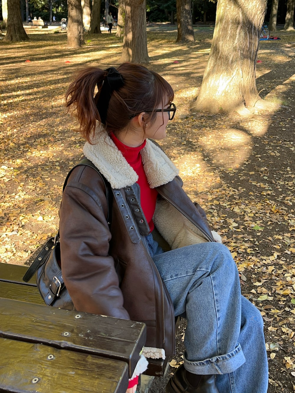 ブラウン系のムートンコート、ブルー系のデニムパンツ、レッド系のニット/セーターを着用したレディースの冬コーディネートの2枚目の写真