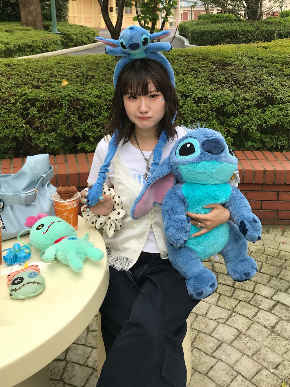 ホワイト系のベスト、ホワイト系のパンプス、ブルー系のカーゴパンツを着用したレディースの夏コーディネートの2枚目の写真
