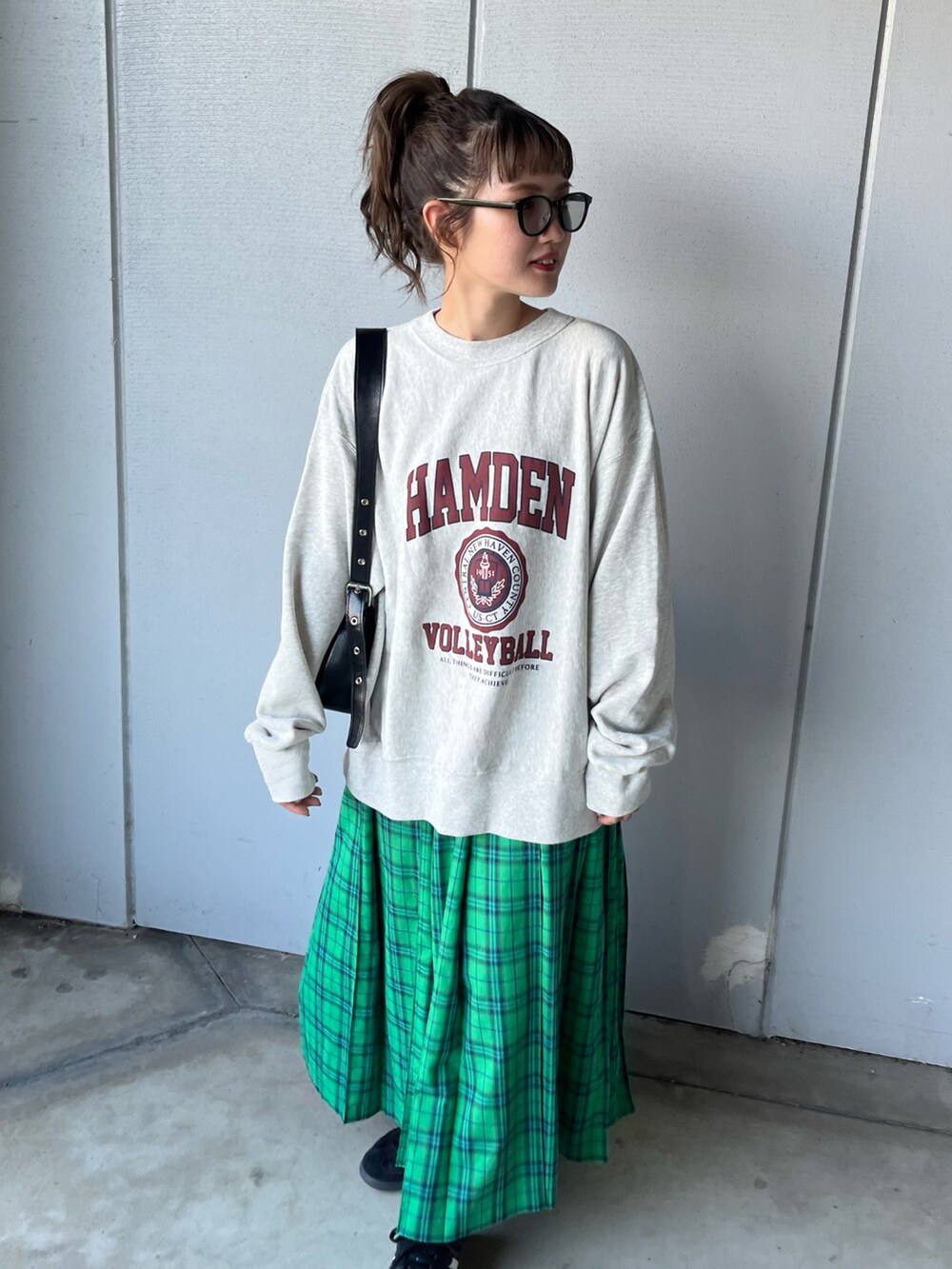 グレー系のスウェット、グリーン系のスカート、ブラック系のスニーカーを着用したレディースの夏コーディネートの2枚目の写真