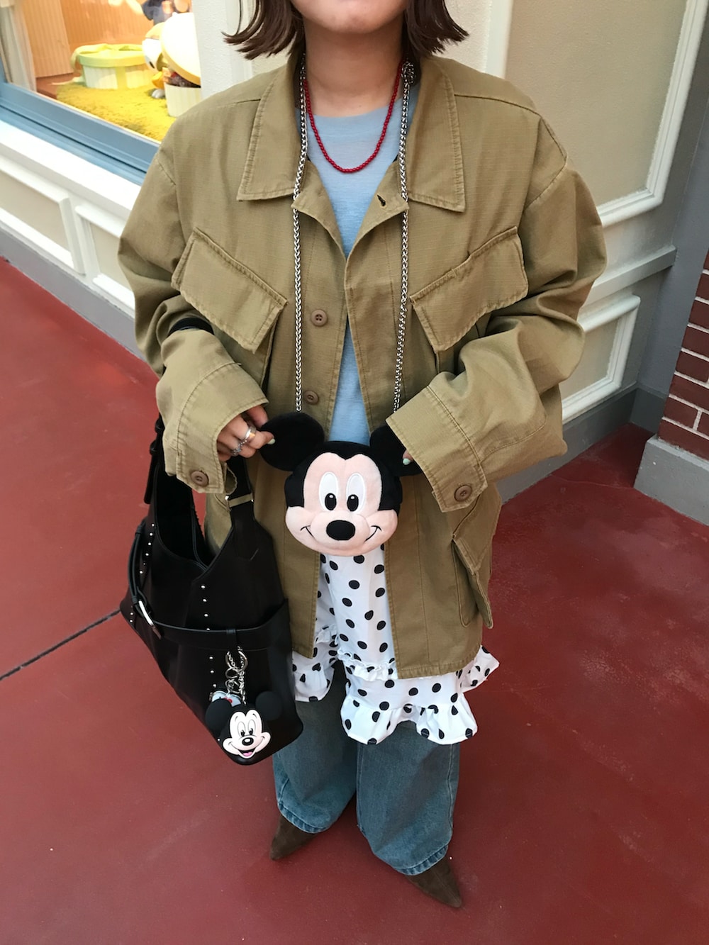 イエロー系のミリタリージャケット、ブルー系のデニムパンツ、ホワイト系のスカートを着用したレディースの春コーディネートの3枚目の写真