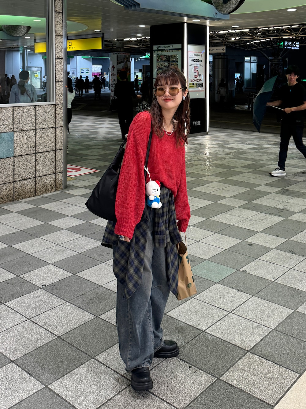 レッド系のニット/セーター、ブラック系のローファー、ブルー系のデニムパンツを着用したレディースの秋コーディネートの3枚目の写真