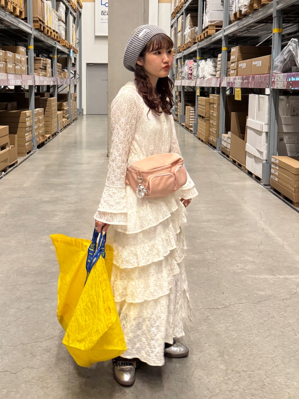 ホワイト系のワンピース、ブルー系のデニムパンツ、シルバー系のスニーカーを着用したレディースの春コーディネートの2枚目の写真