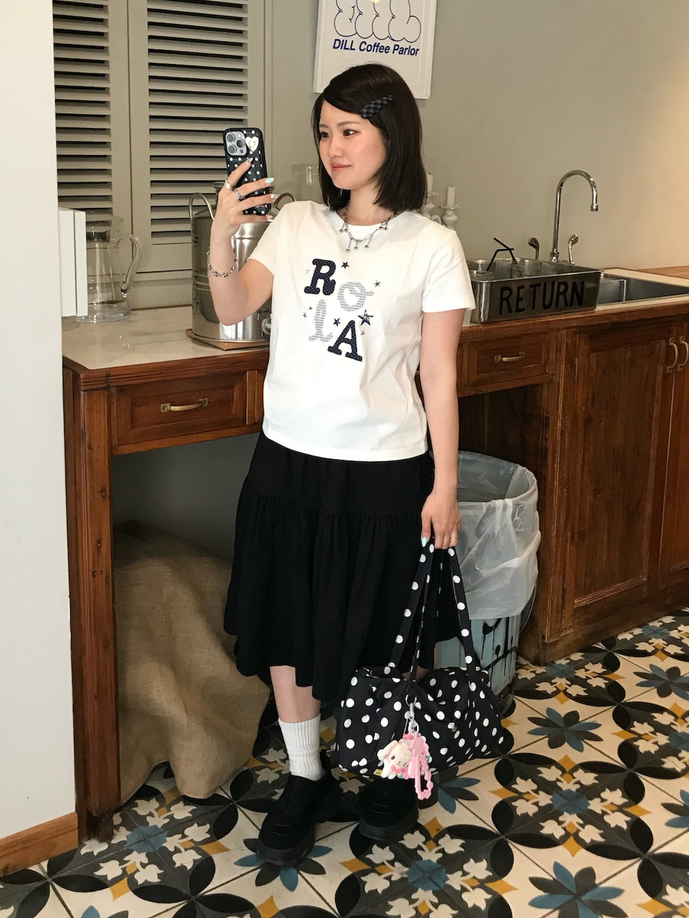 ホワイト系のTシャツ/カットソー、ブラック系のスカート、ブラック系のバッグを着用したレディースの春コーディネートの2枚目の写真