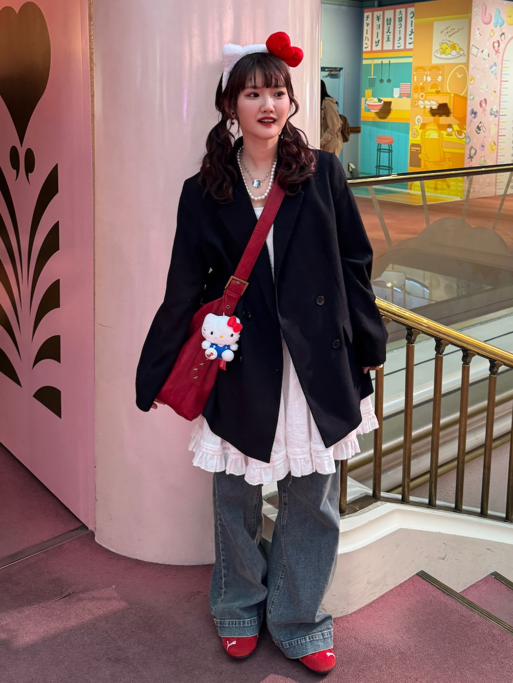 ブラック系のテーラードジャケット、ホワイト系のチュニック、ブルー系のデニムパンツを着用したレディースの春コーディネートの2枚目の写真