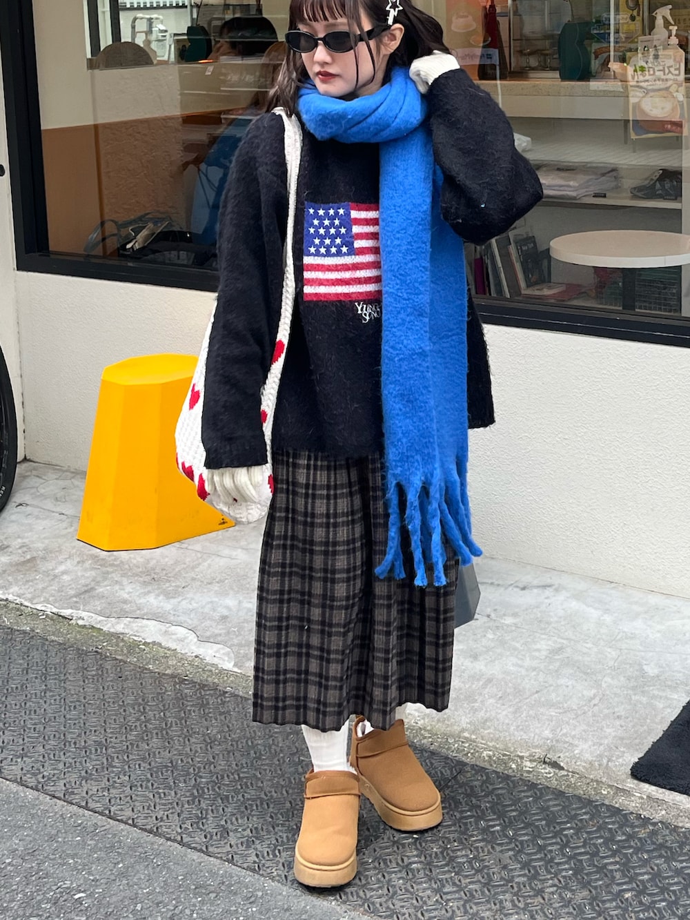 ブラック系のニット/セーター、ブラウン系のスカート、ブルー系のマフラーを着用したレディースの秋コーディネートの2枚目の写真