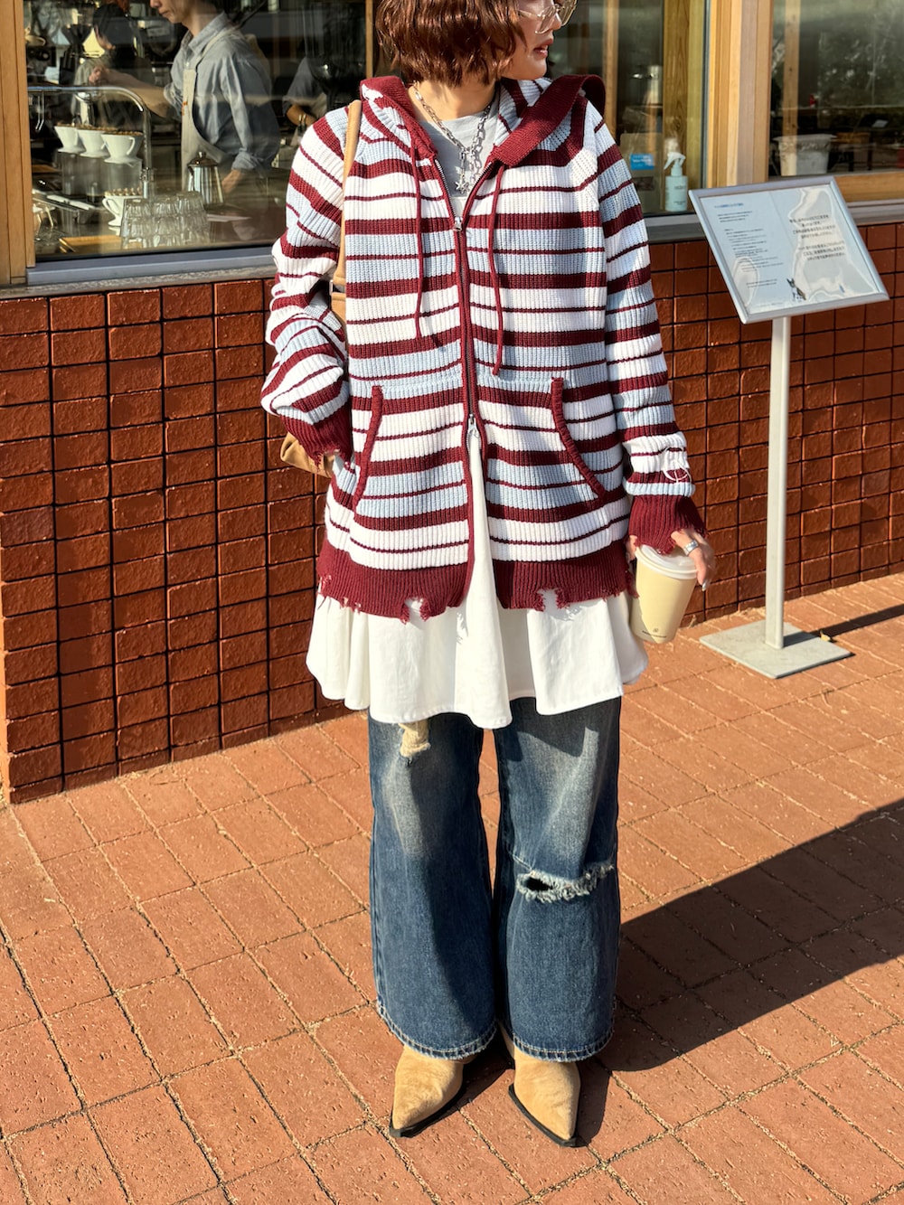 ホワイト系のパーカー、ブルー系のデニムパンツ、ベージュ系のハンドバッグを着用したレディースの冬コーディネートの2枚目の写真