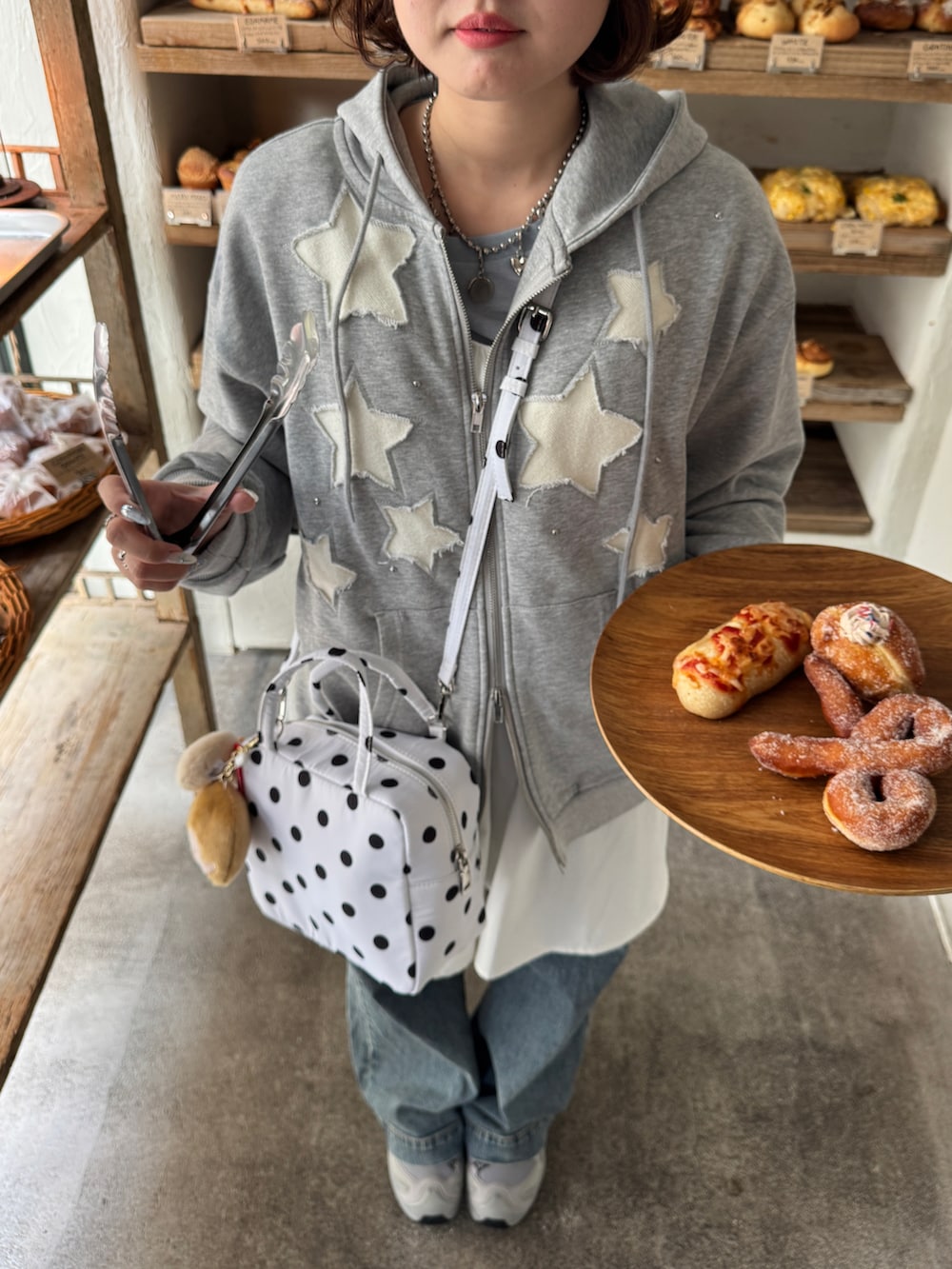 ブルー系のデニムパンツ、シルバー系のスニーカー、グレー系のパーカーを着用したレディースの冬コーディネートの3枚目の写真