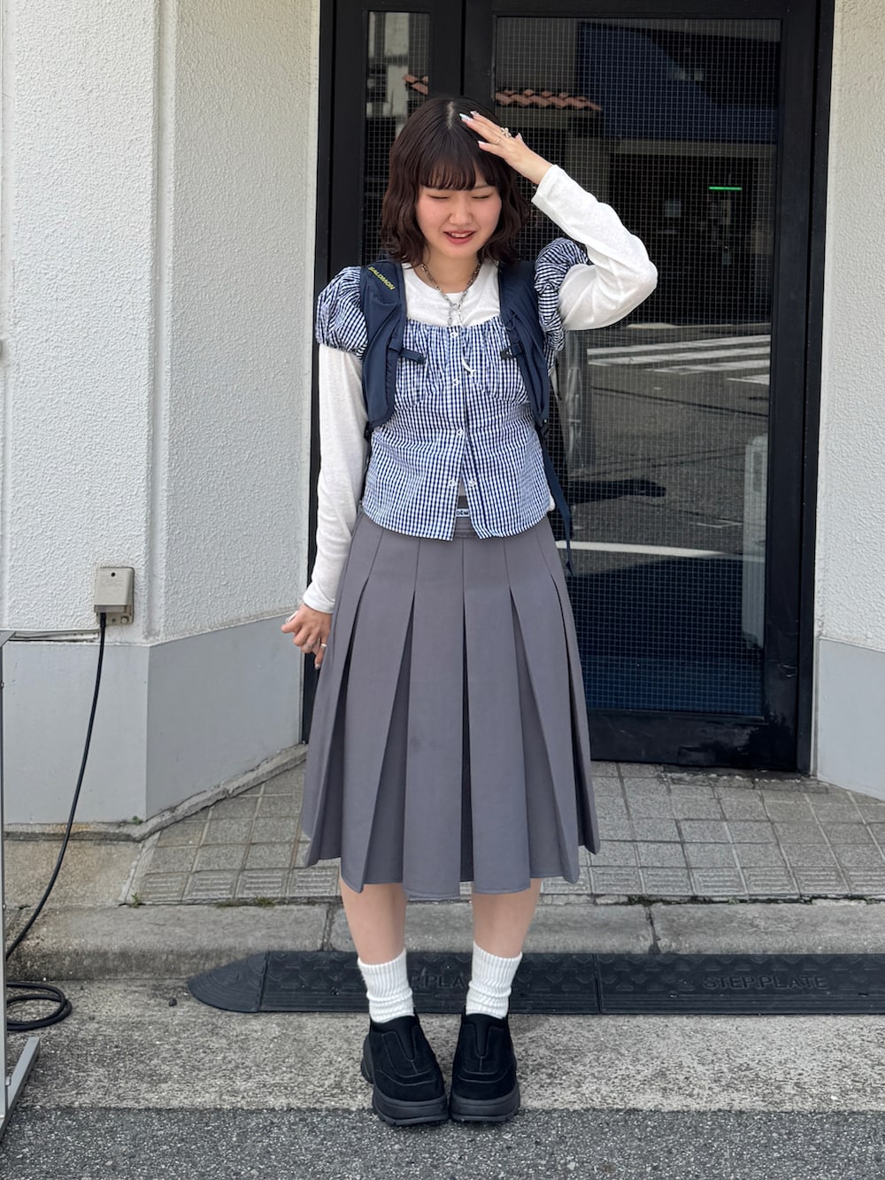 ブルー系のシャツ/ブラウス、ブルー系のバックパック/リュック、グレー系のスカートを着用したレディースの春コーディネートの2枚目の写真