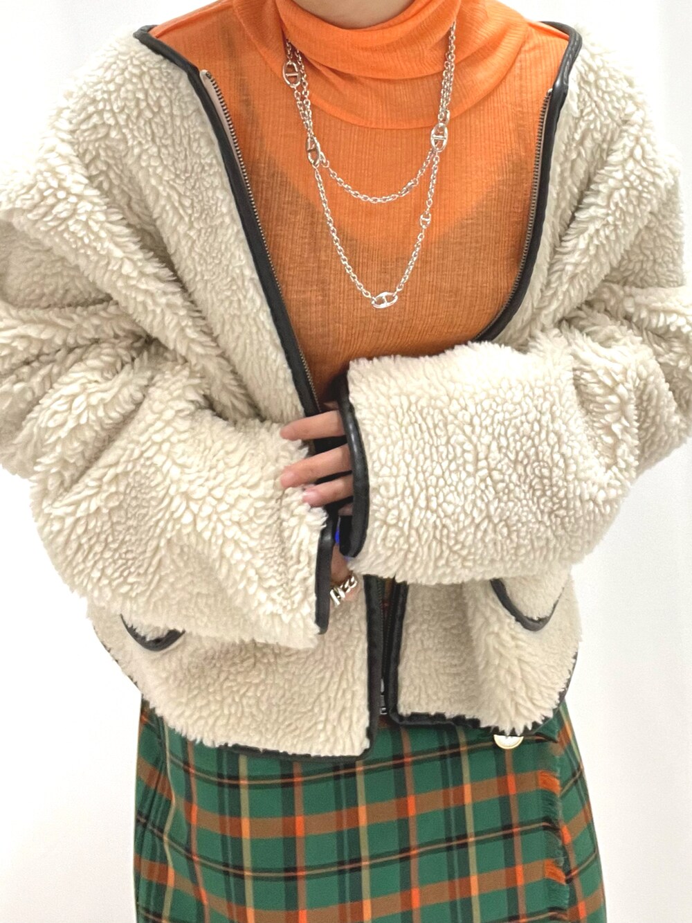 グリーン系のスカート、ホワイト系のブーツ、シルバー系のネックレスを着用したレディースの冬コーディネートの2枚目の写真