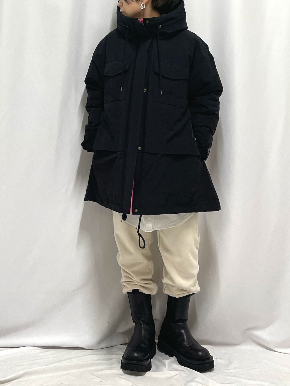 ベージュ系のスウェットパンツ、ブラック系のダウンジャケット/コート、ホワイト系のシャツ/ブラウスを着用したレディースの秋コーディネートの2枚目の写真