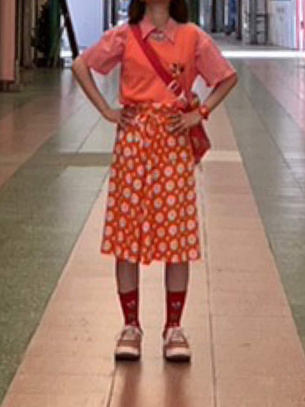 レッド系のスニーカー、オレンジ系のスカート、レッド系のショルダーバッグを着用したレディースの秋コーディネートの2枚目の写真