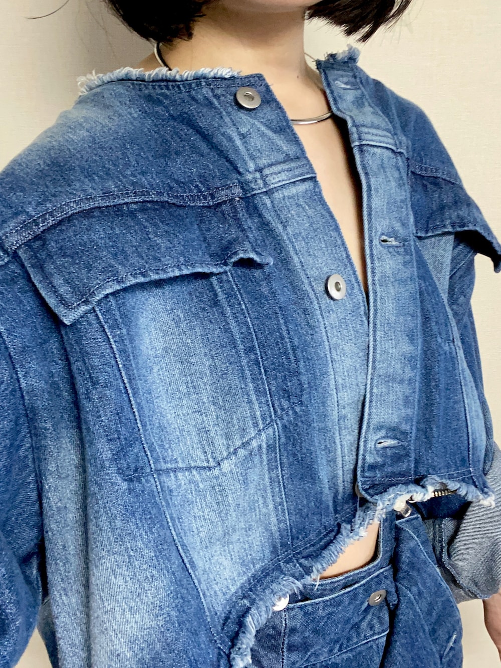 ホワイト系のスニーカー、ブルー系のデニムジャケット、シルバー系のピアス（両耳用）を着用したレディースの秋コーディネートの2枚目の写真