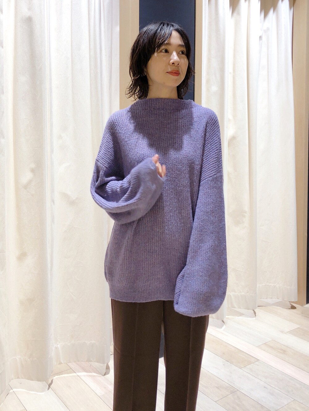 パープル系のニット/セーター、ブラウン系のスラックス、ホワイト系のローファーを着用したレディースの秋コーディネートの2枚目の写真