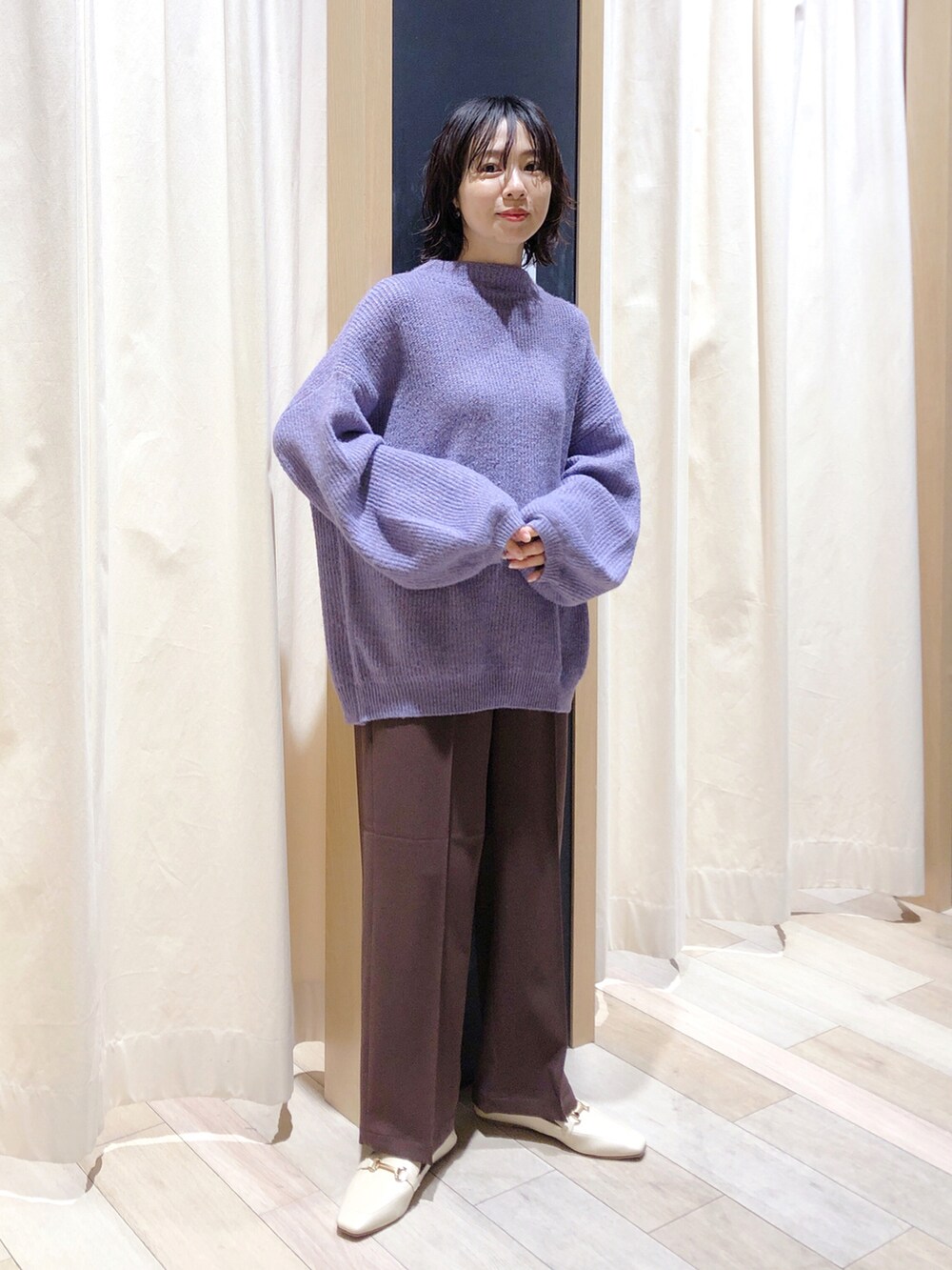 パープル系のニット/セーター、ブラウン系のスラックス、ホワイト系のローファーを着用したレディースの秋コーディネートの5枚目の写真