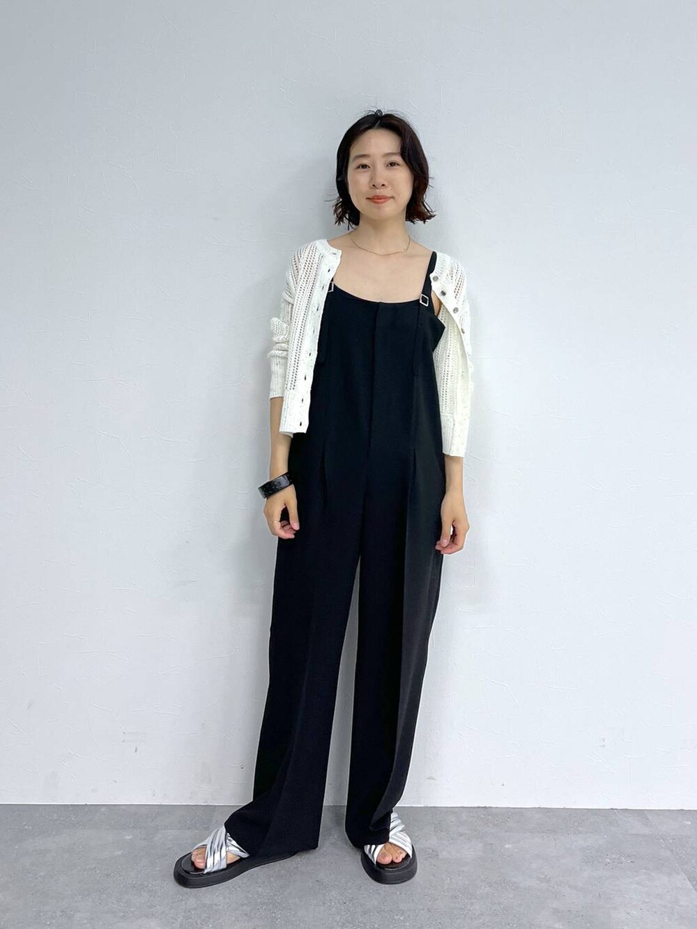 ホワイト系のカーディガン/ボレロ、シルバー系のサンダル、ブラック系のサロペット/オーバーオールを着用したレディースの夏コーディネートの4枚目の写真