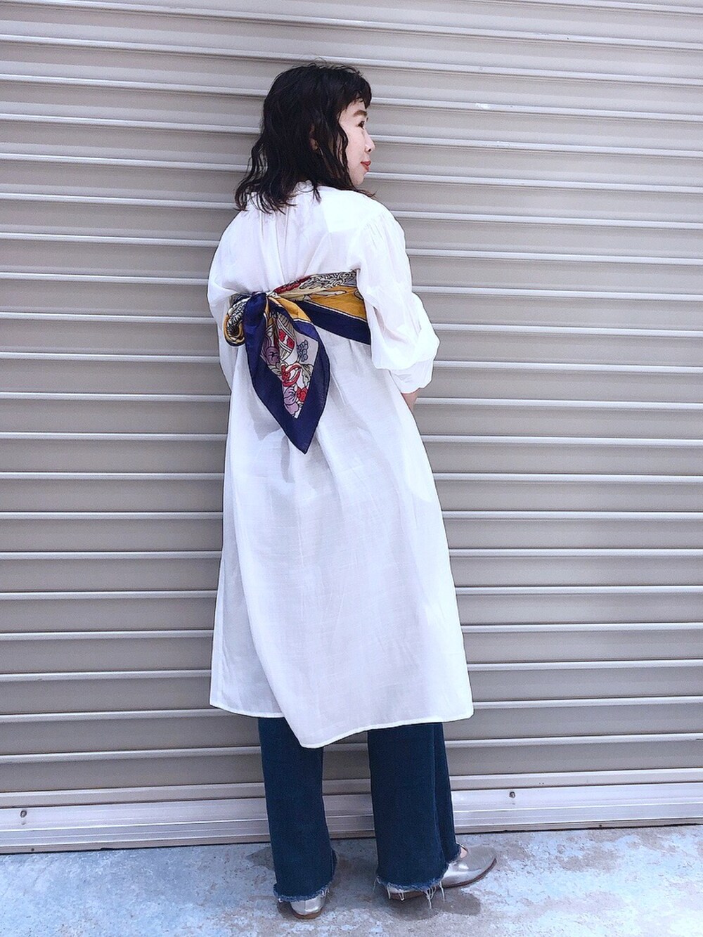 ホワイト系のワンピース、ブルー系のデニムパンツ、シルバー系のパンプスを着用したレディースの冬コーディネートの3枚目の写真