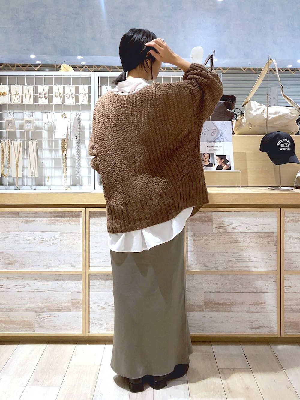 ホワイト系のシャツ/ブラウス、ブラック系のブーツ、グリーン系のスカートを着用したレディースの秋コーディネートの3枚目の写真