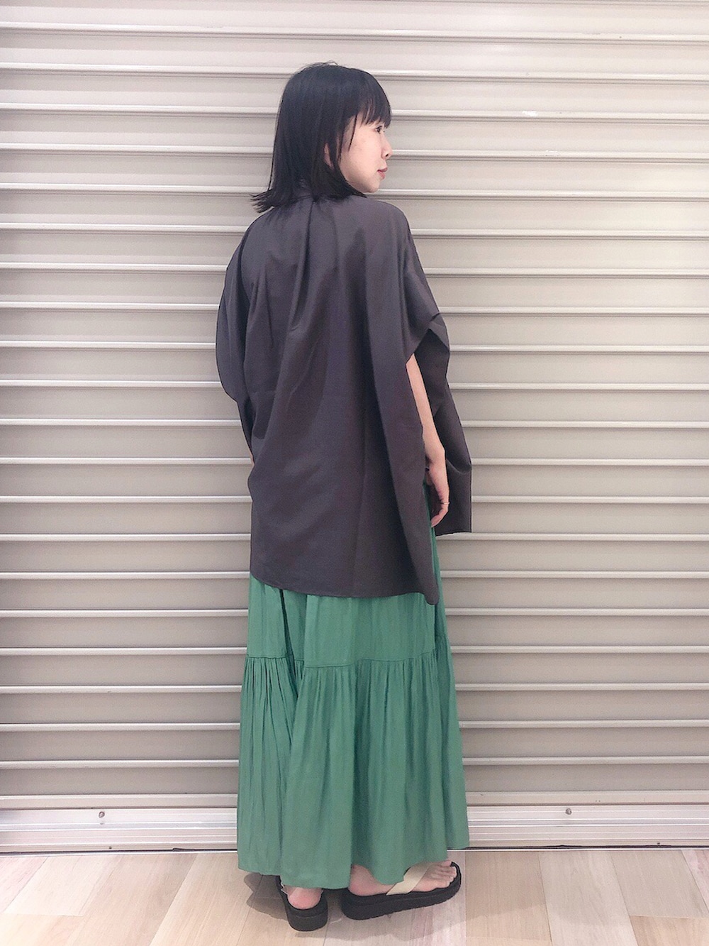 ブラック系のシャツ/ブラウス、グリーン系のスカート、ホワイト系のサンダルを着用したレディースの夏コーディネートの3枚目の写真