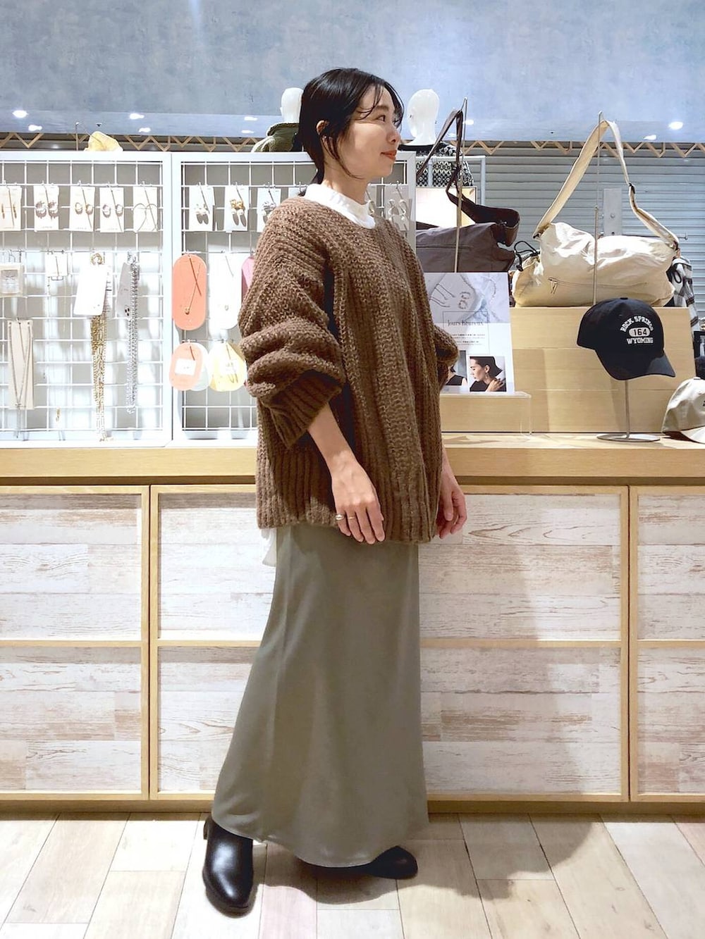 ホワイト系のシャツ/ブラウス、ブラック系のブーツ、グリーン系のスカートを着用したレディースの秋コーディネートの2枚目の写真