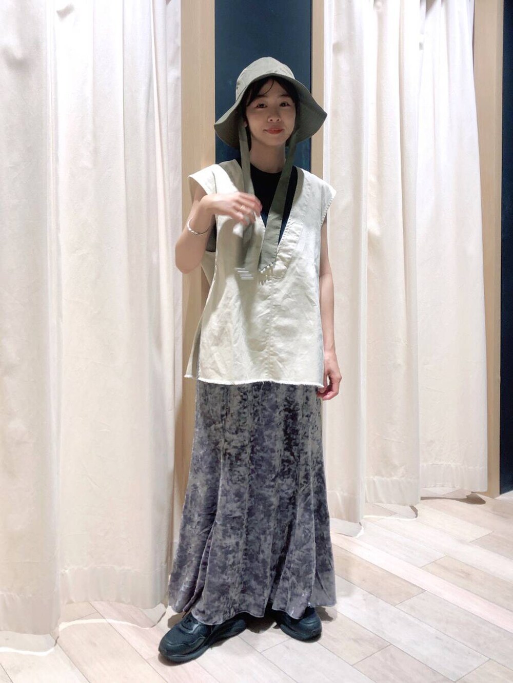 シルバー系のスカート、ホワイト系のベスト、ゴールド系のバングル/リストバンドを着用したレディースの夏コーディネートの4枚目の写真