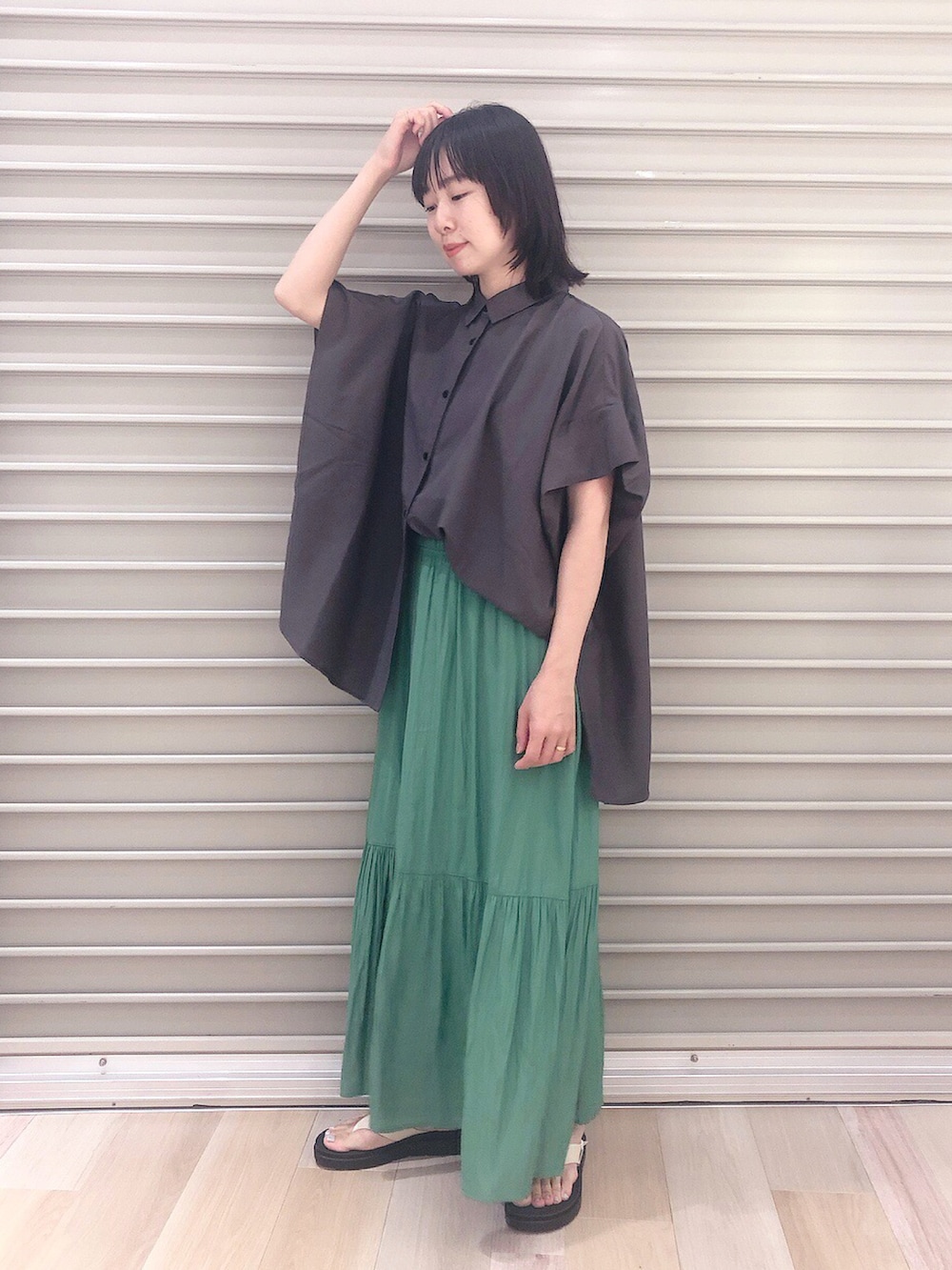 ブラック系のシャツ/ブラウス、グリーン系のスカート、ホワイト系のサンダルを着用したレディースの夏コーディネートの2枚目の写真