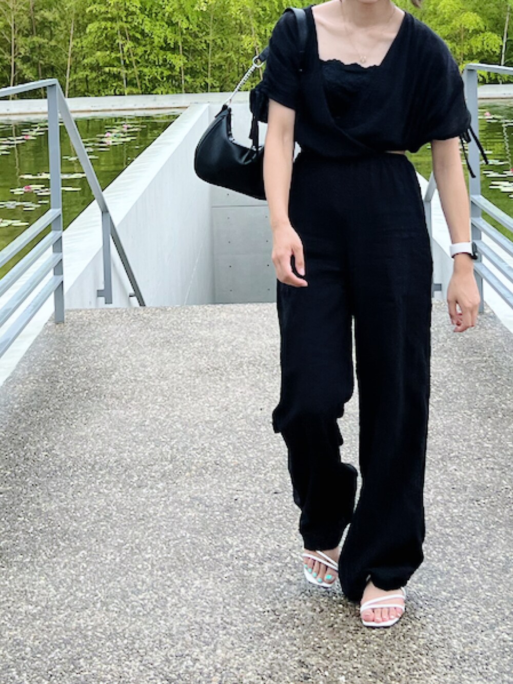 ブラック系のつなぎ/オールインワン、ブラック系のハンドバッグ、ホワイト系のサンダルを着用したレディースの夏コーディネートの2枚目の写真
