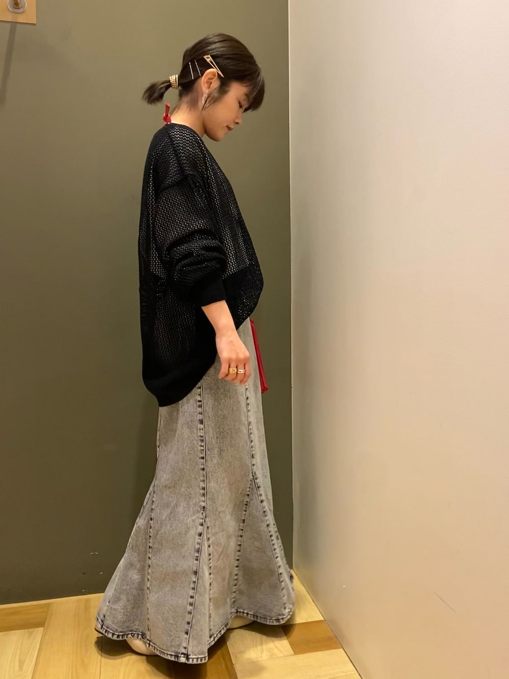 ブラック系のニット/セーター、ブラック系のTシャツ/カットソー、レッド系のショルダーバッグを着用したレディースの春コーディネートの2枚目の写真