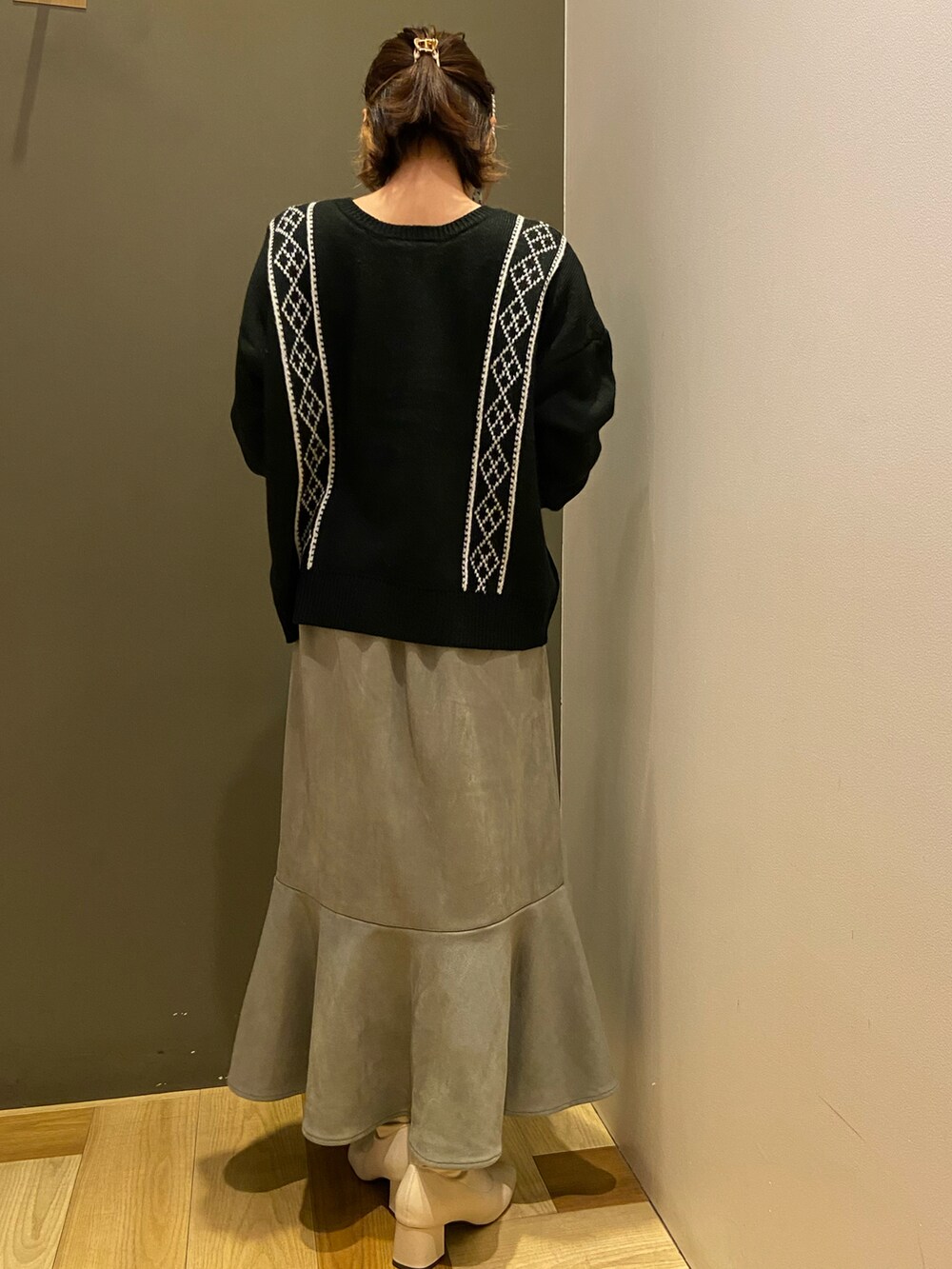 ブラック系のニット/セーター、ブラック系のショルダーバッグ、グリーン系のスカートを着用したレディースの冬コーディネートの3枚目の写真