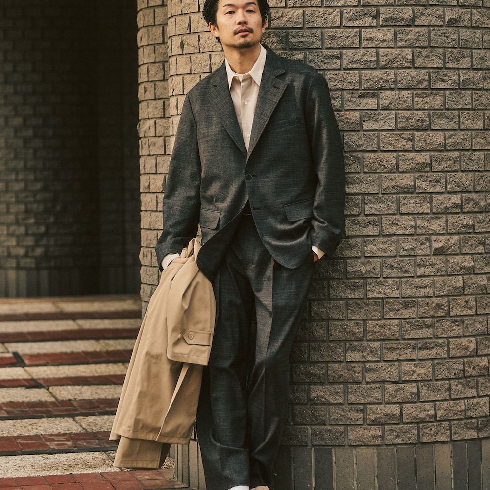 ブラウン系のテーラードジャケット、ベージュ系のステンカラーコート、ブラウン系のスラックスを着用したメンズの冬コーディネートの5枚目の写真