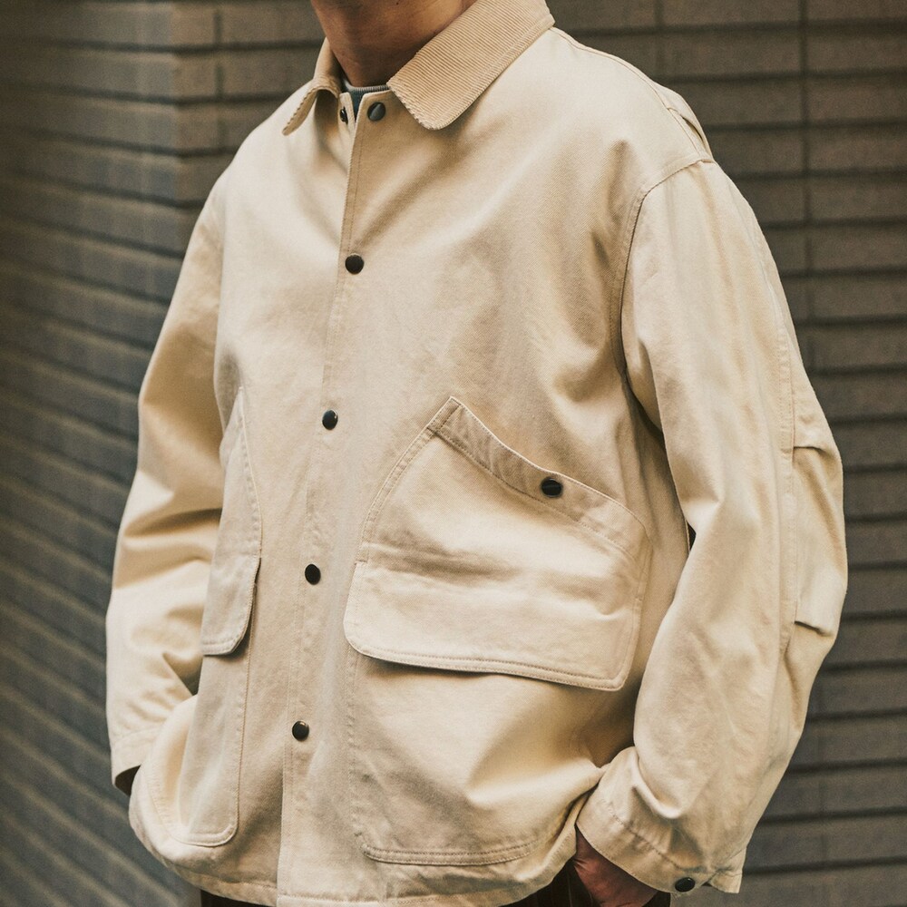 グレー系のニット/セーター、ベージュ系のその他アウター、ブラウン系のスラックスを着用したメンズの冬コーディネートの4枚目の写真