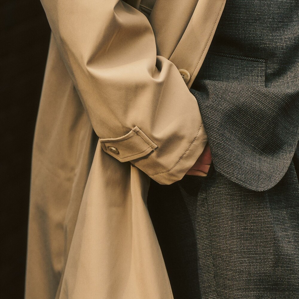 ブラウン系のテーラードジャケット、ベージュ系のステンカラーコート、ブラウン系のスラックスを着用したメンズの冬コーディネートの2枚目の写真