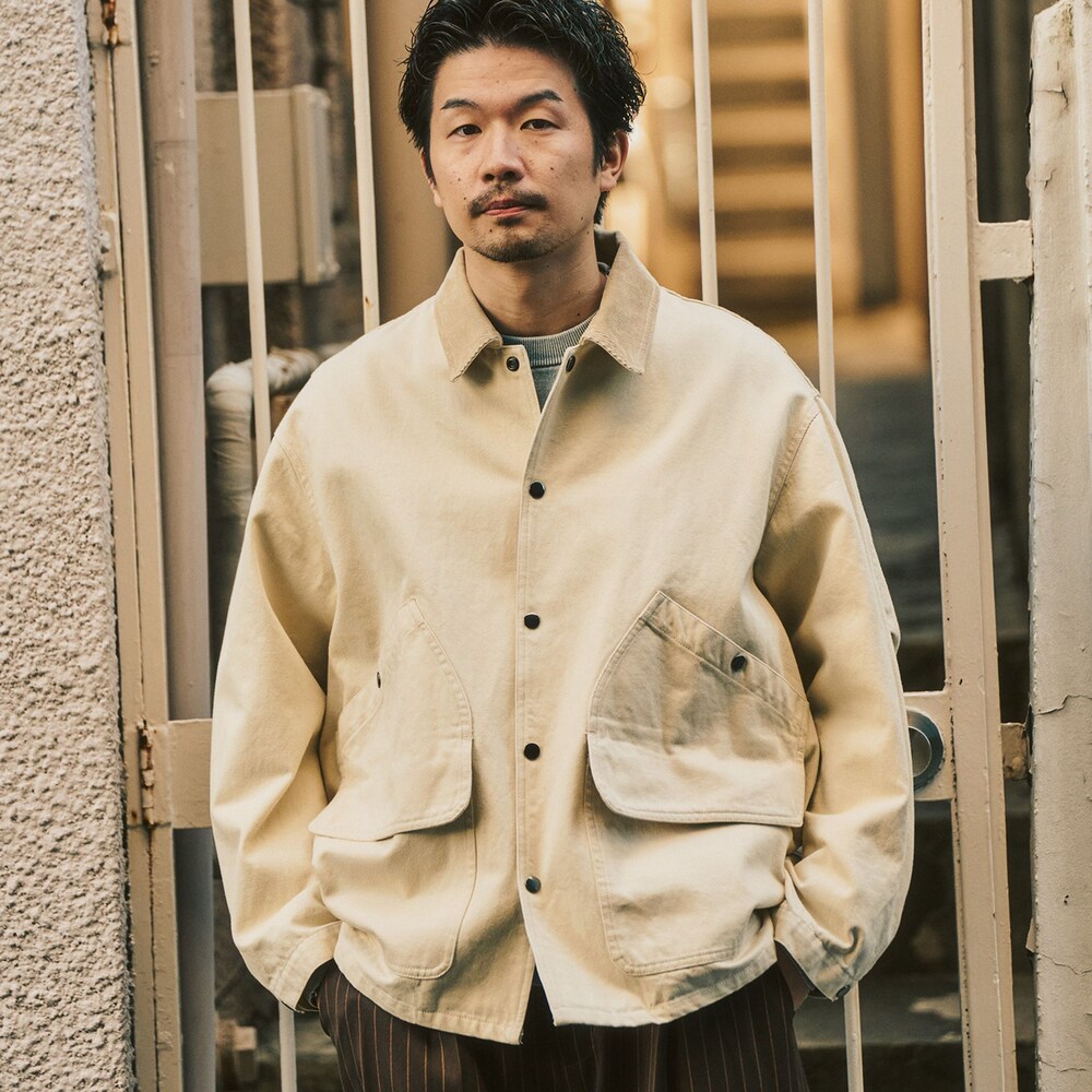 グレー系のニット/セーター、ベージュ系のその他アウター、ブラウン系のスラックスを着用したメンズの冬コーディネートの2枚目の写真