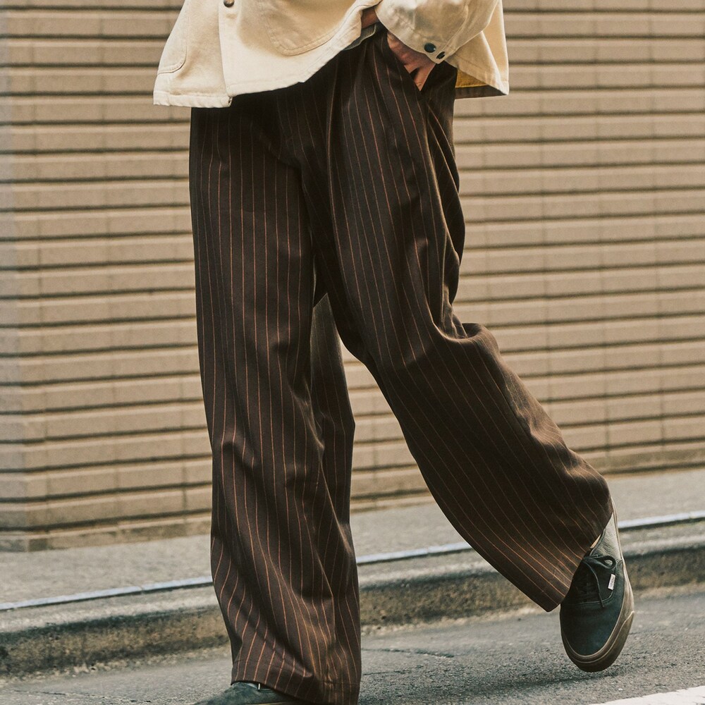 グレー系のニット/セーター、ベージュ系のその他アウター、ブラウン系のスラックスを着用したメンズの冬コーディネートの6枚目の写真