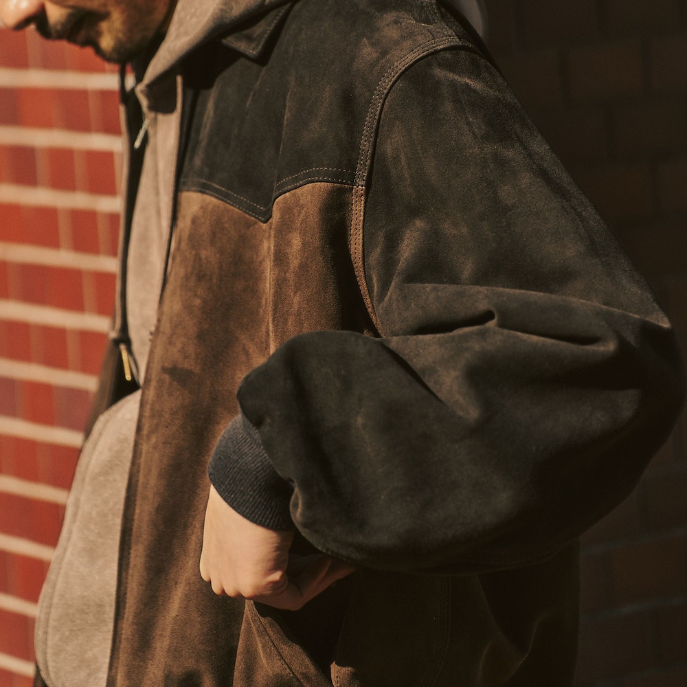 ブラウン系のライダースジャケット、ベージュ系のスラックス、ベージュ系のパーカーを着用したメンズの冬コーディネートの3枚目の写真